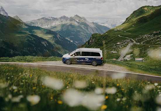 Ein Roadsurfer-Campervan steht am Straßenrand, Blick in die Berge