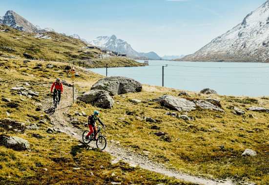 Mountainbiker fahren neben einem See.
