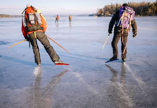 Zwei Nordic Skater mit Rucksäcken auf einem gefrorenen See nahe Uppsala 