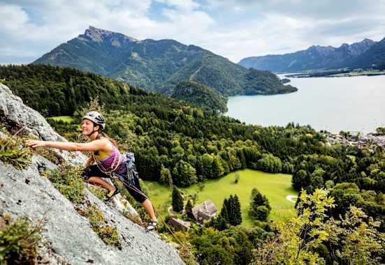 Manuela klettert am Plombergstein, im Hintergrund der türkise Wolfgangsee