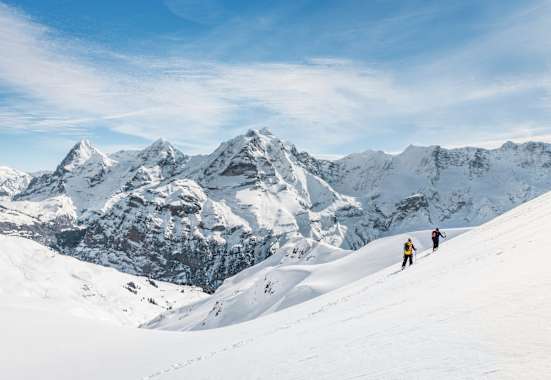 Zwei Schneeschuhwanderer vor atemberaubendem Bergpanorama.