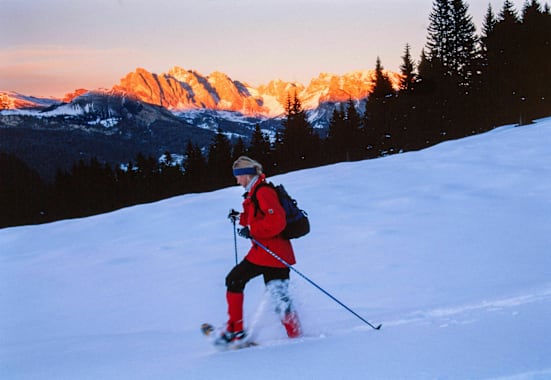 Alpenglühen: Schneeschuhwanderin vor Bergpanorama