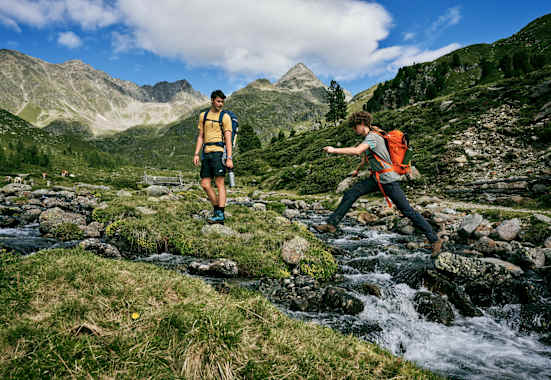 Person springt über Bergbach