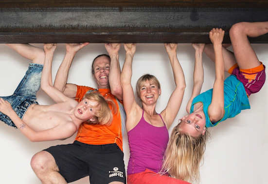 Eine Familie hängt mit den Händen auf einem Eisenträger in der Luft