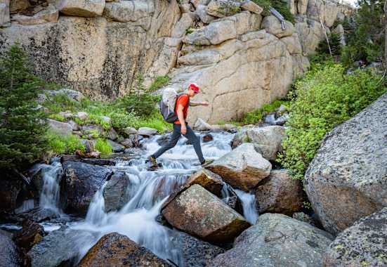 Rab Muon 50L Wanderrucksack mann geht über wasserfall