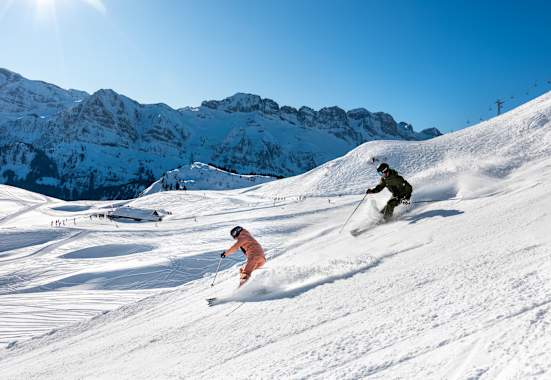 Skifahren in der Schweiz, Berge, zwei Skifahrer, Piste