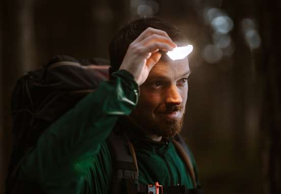 Mann ist in der Natur und benutzt eine Stirnlampe für gute Sicht.