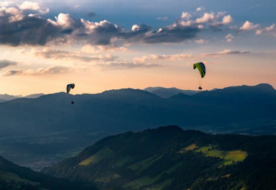 Zwei Personen paragleiten über ein Tal in der Wildschönau.