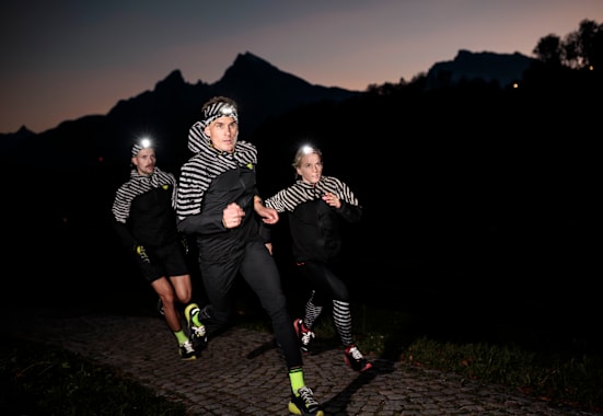 Drei Personen in reflektierender Sportkleidung in der Nacht rennend.