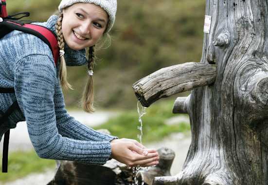 Wanderin schöpft Wasser aus einem Brunnen
