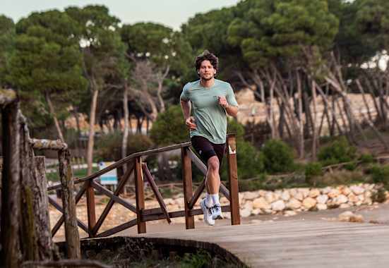 Ein Mann läuft im neuen Trailrunning-Outfit von skinfit über eine Brücke aus Holz.