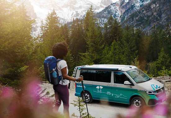 Frau wandert durch die Alpen, unterwegs mit den roadsurfer Camper
