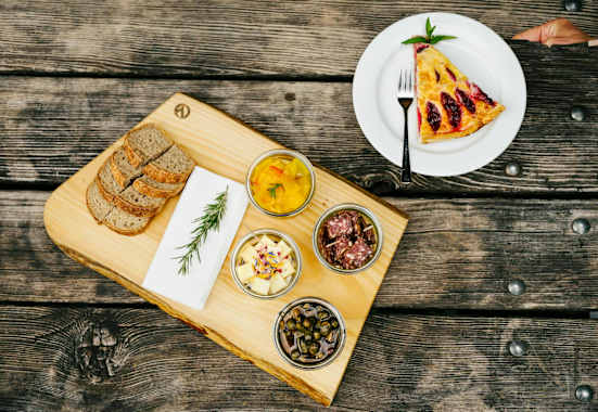 Die Chamanna Cluozza auf 1.882 Meter Seehöhe (oben) ist die einzige bewirtschaftete Hütte im Schweizerischen Nationalpark. Dort werden Nachhaltigkeit und Regionalität vor allem seit dem Umbau vor drei Jahren sehr ernst genommen: Das gilt für natürliche Baumaterialien wie Kalk und Stampflehm, die 30.000 Lärchenschindeln – und die Zutaten für die Speisen, etwa Alpentapas und Zwetschkenkuchen (unten).