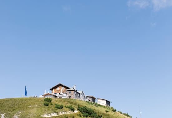 Oberhalb von Garmisch-Partenkirchen auf dem Gipfel des Wank im Estergebirge steht das Wankhaus direkt neben dem Gipfelkreuz.
