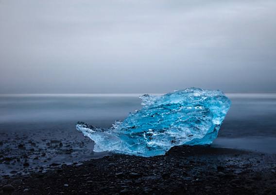 Eisblock im Nebel am schwarzen Sandstrand, Jökulsárlón Gletscherlagune. Langzeitbelichtung.
