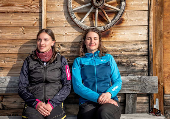 Zwei Besucher genießen die Sonnenstrahlen auf der Hütte.