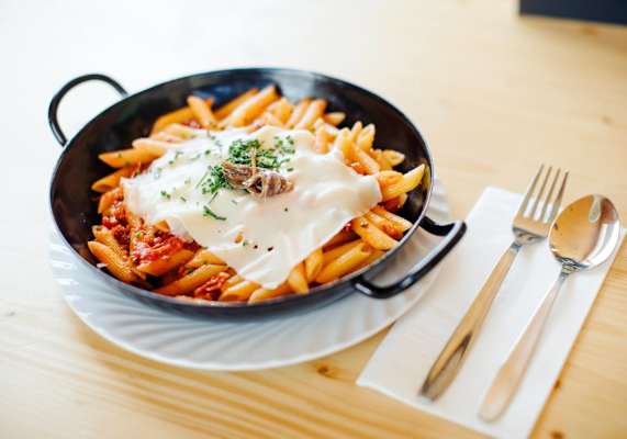 Penne serviert mit Tomatensauce und frischen Kräutern
