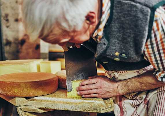 Der Wirt schneidet den Almkäse.