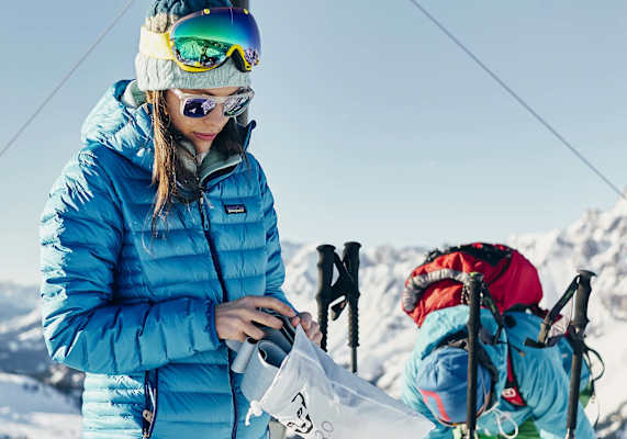 Eine Frau fellt ihre Skier am Gipfel ab.