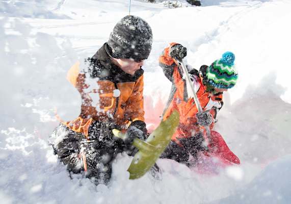 Zwei Kindern schaufeln den Schnee.