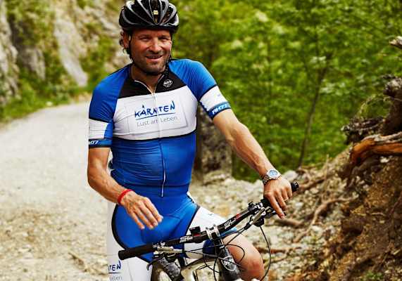 Radfahrer im Fahrraddress auf einem Mountainbike am Berg