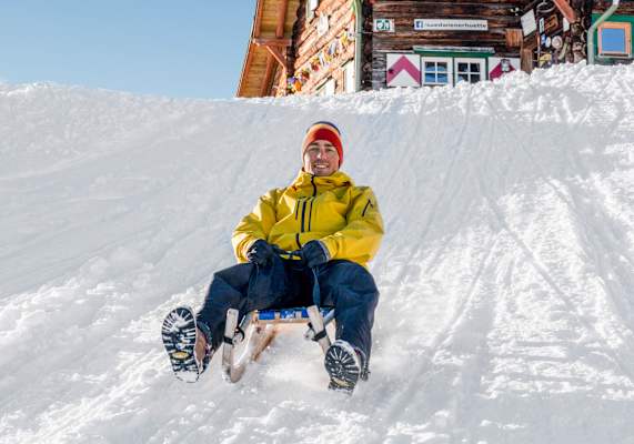 Ein Gast der Südwiener Hütte beim Rodeln ins Tal