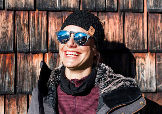 Eine Frau genießt die Sonnenstrahlen vor der Hütte