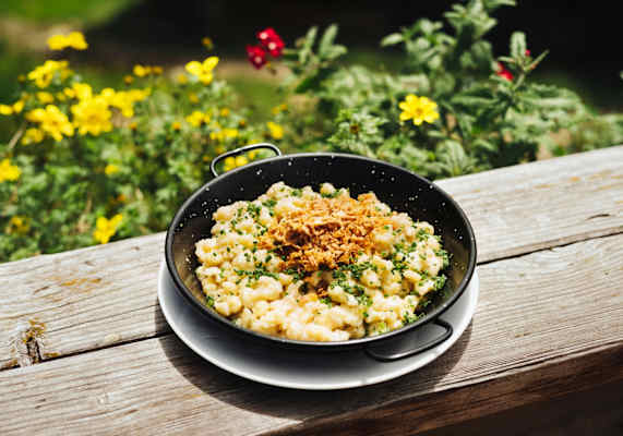 Käsespätzle mit Röstzwiebeln in einer Rein serviert.
