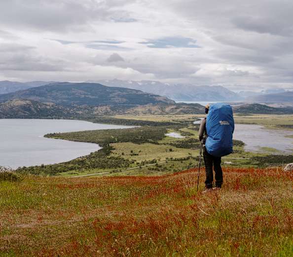 Wanderer steht in Patagonien inmitten einer weiten Landschaft und blickt in die Ferne