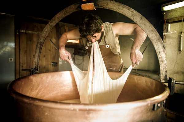 Alles Handarbeit: Raphael holt mit Bögli und Tuech den Käse aus dem Kessel.