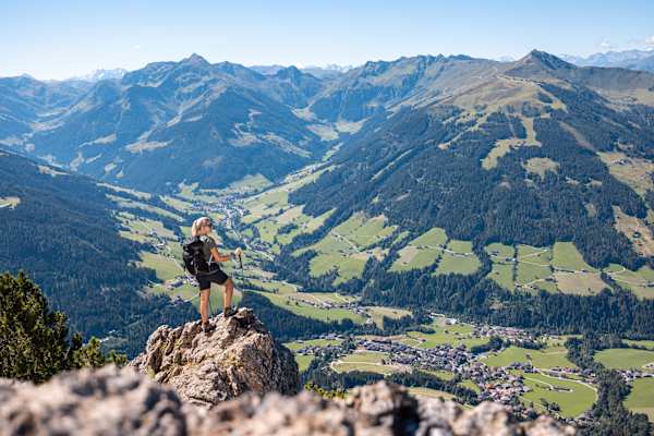 Frau steht auf einem Felsen der Gratlspitze und blickt hinunter ins Alpbachtal.