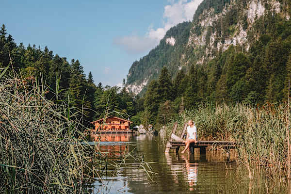 Frau sitzt auf einem Steg am Berglsteinersee bei Breitenbach in der Ferienregion Alpbachtal.