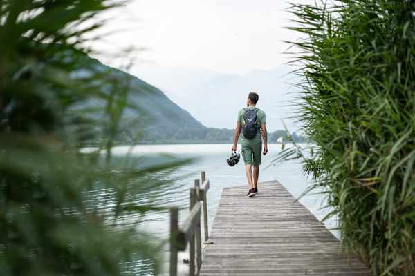 Ein Mann steht auf einem Holzsteg am Ufer des Kalterer Sees.