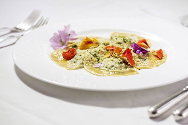 Ein Teller mit Südtiroler Schlutzkrapfen dekoriert mit Blüten