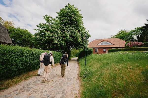 Wanderer gehen auf ein verstecktes Dorf auf der Insel Rügen zu.