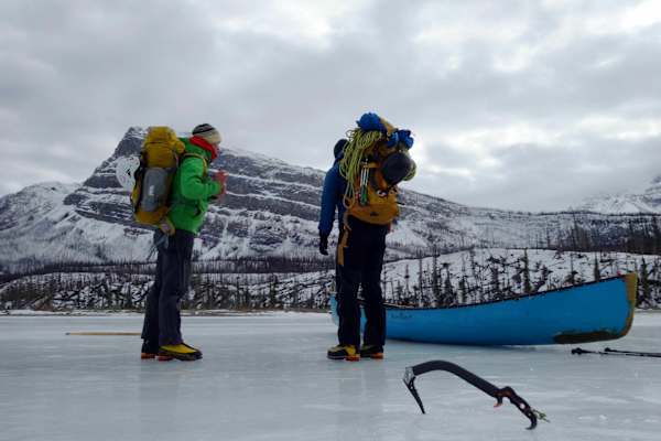 Eiskletterer mit Kanu auf zugefrorenem Fluss