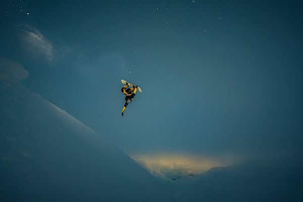 Ein Snowboarder wagt im letzten Abendlicht einen Sprung.