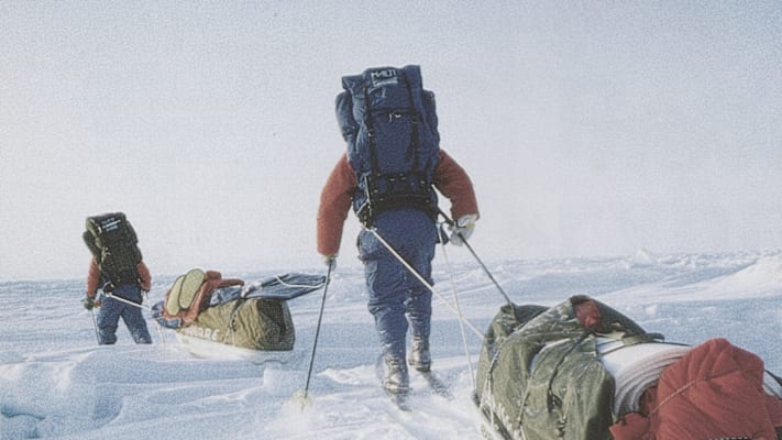 Zwei ausgerüstete Personen durch Schnee und Eis mit ihrer Ausrüstung.