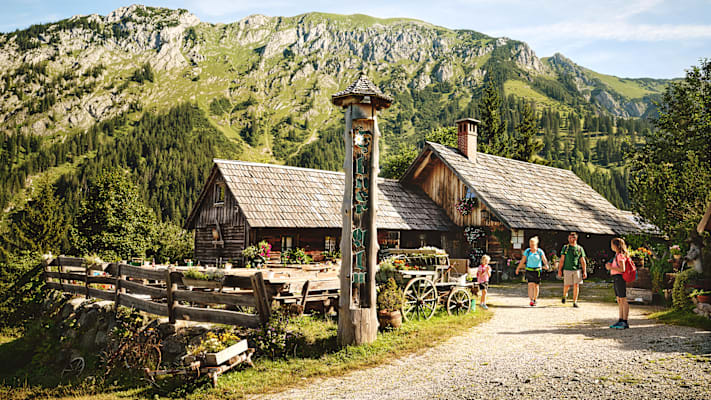 Eine Familie wandert im Sommer im Gesäuse auf eine Almhütte.