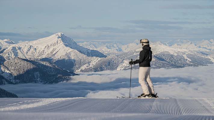 ein skifahrer steht auf der piste und blick in die schneebedeckte berglandschaft
