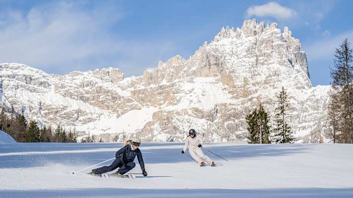 zwei skifahrer fahren eine piste hinunter im skigebiet 3 zinnen