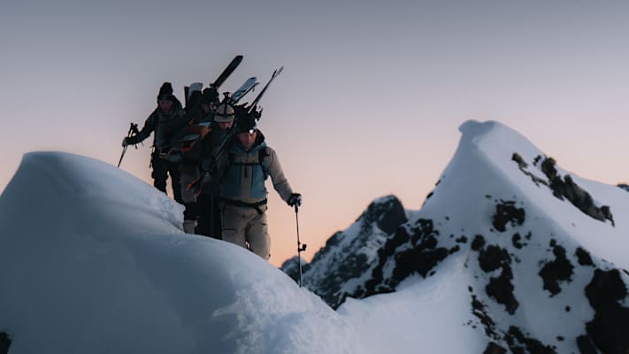 vier männer am berg mit ski am rücken