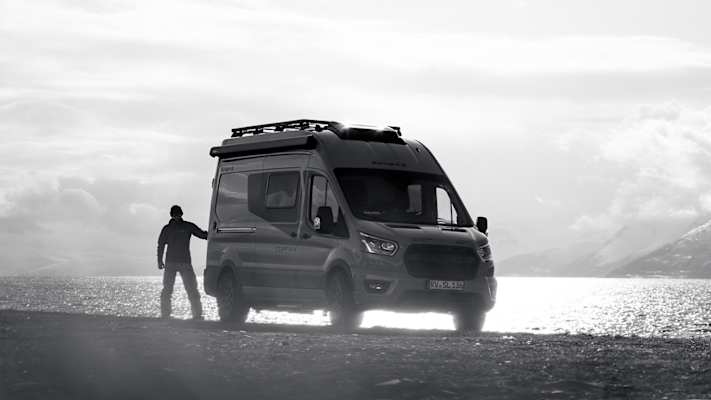 Campervan steht am Ufer eines Fjords in Nord-Norwegen, umgeben von Bergen und winterlicher Landschaft.