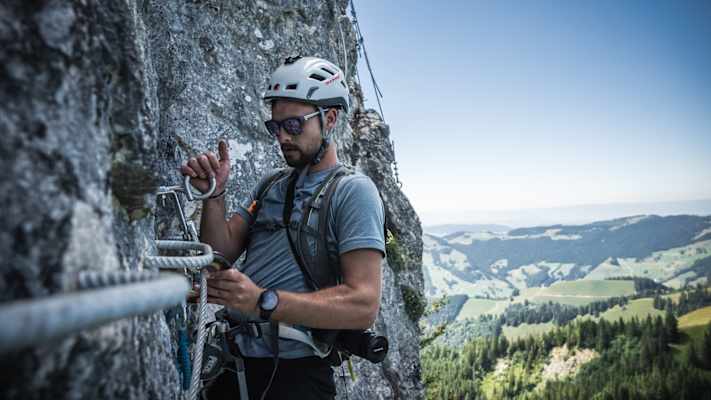 Ein Klettersteiggeher in der senkrechten Wand der Via Ferrata Charmey.