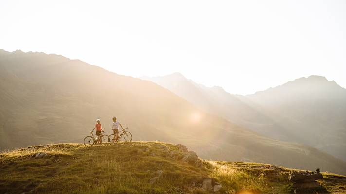 Eine Radfahrerin und ein Radfahrer genießen die Aussicht in Naturns.