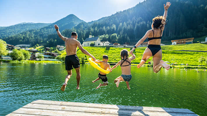 Eine Familie springt in See in den Badesee.