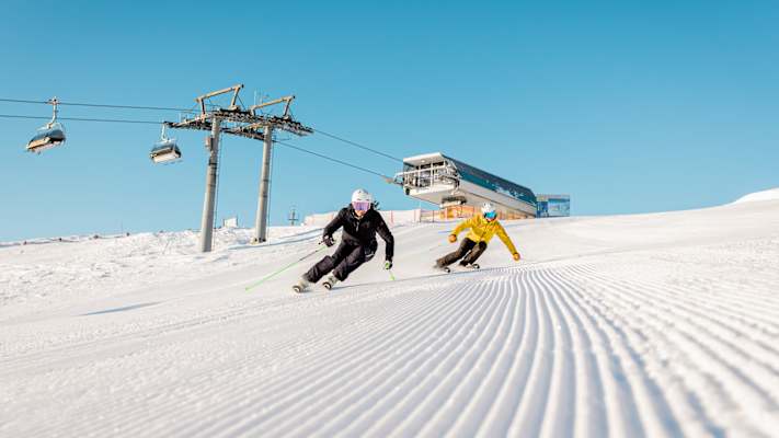 Zwei Skifahrer fahren die perfekt präperierten Pisten hinunter.