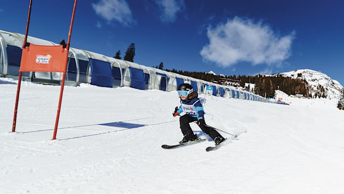 Ein Kind fährt den Übungshang im Skigebiet Kappl hinunter und fährt dabei an einem Tor vorbei.