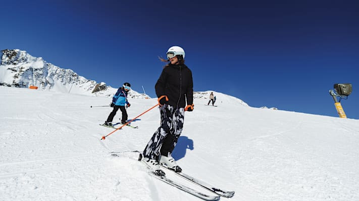 Eine Mutter fährt mit ihrem Kind einen Hang im Skigebiet Kappl hinunter.