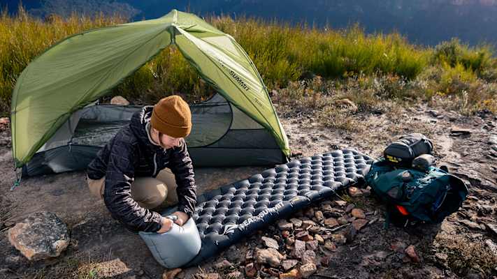 Camperin richtet Sea to Summit Ether Light XR Isomatte neben Zelt ein – ultraleichte Campingausrüstung für Komfort in den Bergen